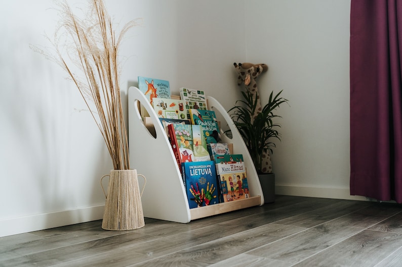 Solid wood floor Montessori floor bookshelf. All books are stored picture-forward. Side panels painted in white, middle parts oiled in clear oil. Is sturdy and robust, all corers are rounded so it is safe to use even for babies.