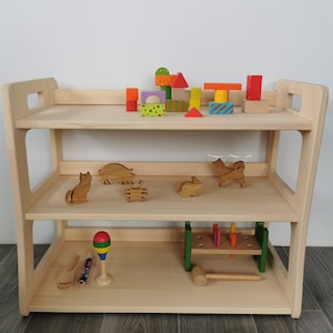 Solid wood Montessori shelf. Natural wood, untreated with children toys in it. Height: 57 cm, width: 71 cm, depth: 37 cm.