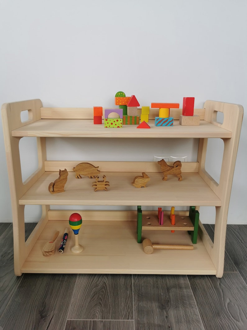 Solid wood Montessori shelf. Natural wood, untreated with children toys in it. Height: 57 cm, width: 71 cm, depth: 37 cm.