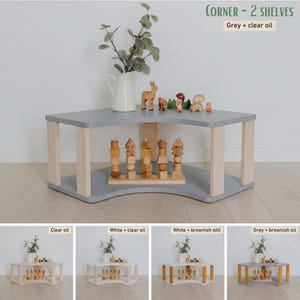 May include: A gray corner shelf unit with two levels and light-colored wooden legs. The top shelf holds a white pitcher with greenery and wooden toys. The text "CORNER - 2 SHELVES" and "Grey + clear oil" is visible.