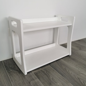 The smallest Montessori shelf is painted all white. It consists of 2 shelves, dimensions: height - 46 cm, width - 54 cm, depth - 30 cm. The shelf can be used to store a child's toys or shoes.