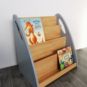 The Montessori bookshelf is photographed from the side. The sides are painted light grey, the middle parts are oiled with brownish oil.