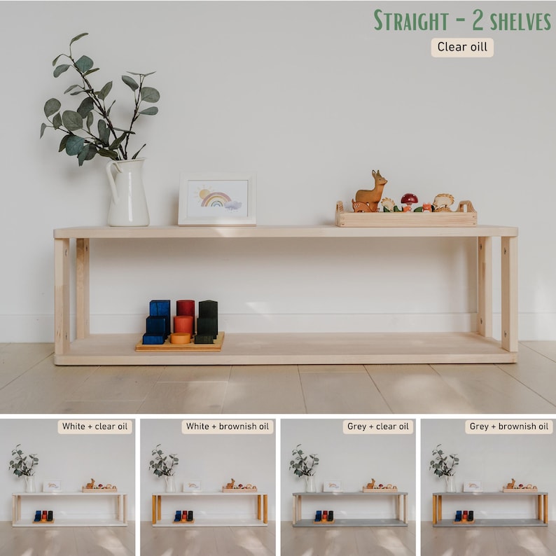 May include: A light-colored wooden shelf unit with two shelves. The unit is rectangular and has a natural wood finish. The top shelf holds a white vase with greenery, a framed picture, and a wooden tray with toys. The text "STRAIGHT - 2 SHELVES" and "Clear oil" are visible.