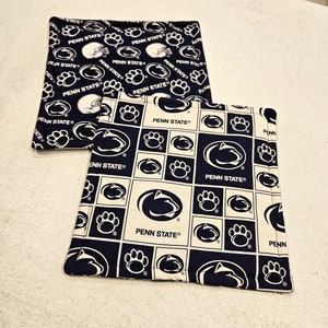 May include: Two black and white fabric pot holders with the Penn State Nittany Lion logo and the words "Penn State" repeated throughout.