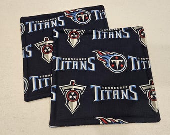 May include: Two black fabric pot holders with a repeating pattern of the Tennessee Titans logo, the words "Tennessee Titans", and a sword with stars.