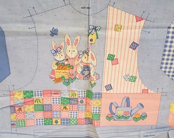May include: A blue and white fabric with a patchwork design featuring bunnies, a watering can, and a bird. The fabric is perfect for quilting or crafting.