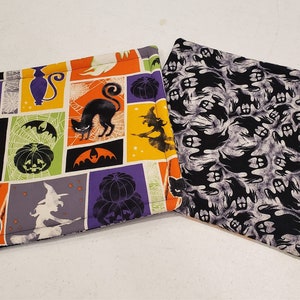 Peut inclure: Deux maniques de cuisine sur le thème d'Halloween. L'une est noire avec un motif de fantômes blancs. L'autre est multicolore avec un motif en patchwork représentant des chats, des citrouilles, des chauves-souris et des sorcières.