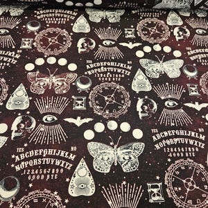 Könnte beinhalten: Dunkelburgunderfarbener Stoff mit einem sich wiederholenden Muster weißer okkulter Symbole. Das Design umfasst Ouija-Bretter, Schmetterlinge, Uhren, Totenköpfe und Augen. Der Stoff hat eine Vintage-Gothic-Ästhetik.