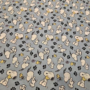 Peanuts Snoopy and Woodstock playing on blue background material is sold by the yard and is 100% cotton