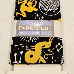 Könnte beinhalten: Ein schwarzer Stoffzuschnitt mit einem gelben Himmelsdesign mit Mond, Sternen und Tierkreisfiguren. Der Stoff ist mit "1 Yard Fabric Cut" gekennzeichnet und misst 91,49x111,8 cm. Er besteht aus 100 % Baumwolle.