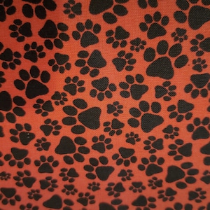 Dog Paws material on red background is sold by the yard and is 100% cotton fabric