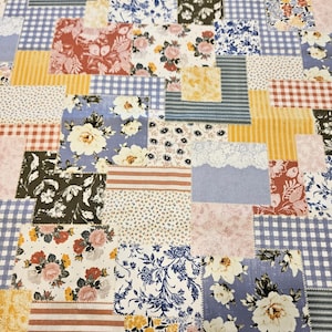 Puede incluir: Tela de patchwork con una mezcla de estampados florales, a rayas y de cuadros en tonos azules, rojos, amarillos y blancos. El diseño está compuesto por cuadrados de diferentes tamaños y texturas, creando una estética vintage y artesanal.