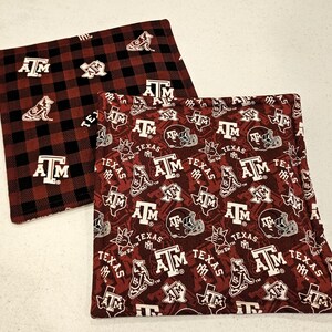 May include: Two square fabric items with maroon and white patterns. One features a black and maroon plaid with "A&M" and a dog logo. The other has a repeating pattern of "A&M", football helmets, and the word "TEXAS".