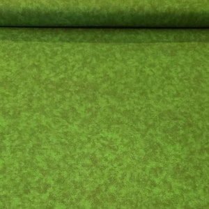 Op de afbeelding: Een close-up van een groene stof met een gemarmerde textuur. De stof heeft een subtiel, gevlekt patroon dat lijkt op een grasveld.