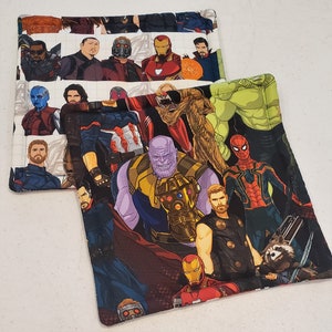 May include: Two fabric squares with a colorful collage of superhero characters. The top square features characters from the Avengers, including Iron Man, Captain America, Thor, and Hulk. The bottom square features characters from the Guardians of the Galaxy, including Star-Lord, Gamora, Drax, and Rocket Raccoon.