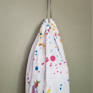 May include: White drawstring bag with colorful paint splatters and a toucan illustration. The bag has the text "Toucan Tango" printed on the bottom.