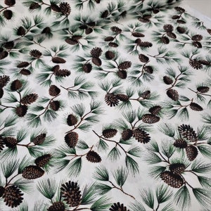 May include: White fabric with a repeating pattern of green pine branches and brown pine cones. The fabric has a subtle shimmer.