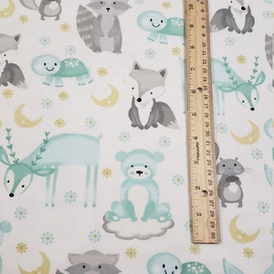 May include: White fabric with a repeating pattern of woodland animals in shades of gray, blue, and yellow. The animals include a deer, fox, raccoon, bear, squirrel, and turtle. There are also small yellow flowers and crescent moons.
