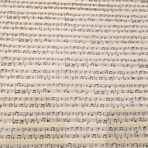 Puede incluir: Primer plano de partituras envejecidas. El papel tiene un aspecto amarillento y vintage. Notas musicales y símbolos negros están densamente impresos en la página en líneas horizontales, creando un patrón texturizado. La imagen evoca la historia y la música clásica.