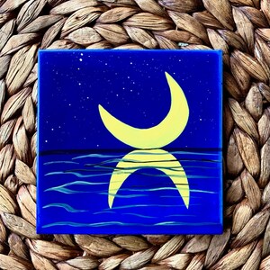 May include: A painting of a crescent moon in yellow against a dark blue background with white stars. The moon is reflected in the water below, which is depicted in dark blue with white waves.