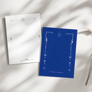 Puede incluir: Dos hojas de papel rectangulares, una blanca y otra azul, con diseños celestiales. La hoja blanca tiene un diseño de sol y luna, mientras que la hoja azul presenta un diseño similar con lunas y estrellas.