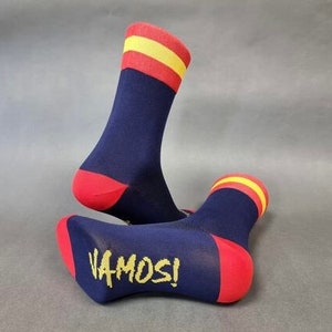 May include: A pair of blue socks with red and yellow stripes. The socks have the word "VAMOS!" written on them.