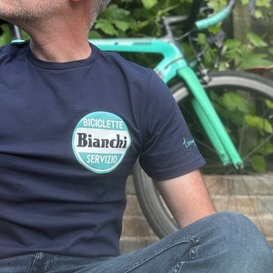 May include: A navy blue t-shirt with a white and teal circular logo that says "Biciclette Bianchi Servizio".