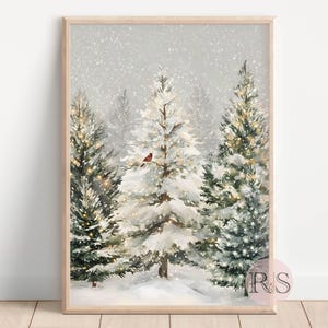 May include: A framed winter landscape print featuring snow-covered evergreen trees. A small red bird perches on a snow-laden tree branch. The artwork has a soft, watercolor style with a light gray sky and falling snow.