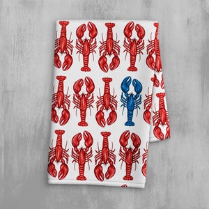 以下が含まれることがあります： 赤いロブスターが繰り返し描かれた白いキッチンクロス。1匹のロブスターが青色です。