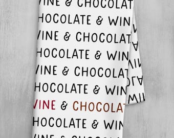 Könnte beinhalten: Weißes Küchentuch mit sich wiederholendem Text in Schwarz: "VINE & CHOCOLAT" und "HOCOLATE & WIN". Die Wörter "VINE" und "CHOCOLAT" sind in Burgunderrot und Braun. Das Handtuch ist gefaltet.