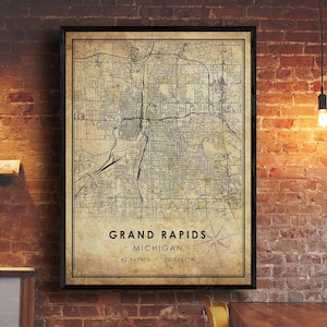 May include: A vintage-style map print of Grand Rapids, Michigan. The map is in black and white with a beige background. The city name and coordinates are printed at the bottom of the map.