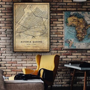 May include: A vintage style map print of Astoria, Queens, New York City. The map is framed and hanging on a brick wall. The map shows the streets and landmarks of the neighborhood. The text on the map reads "Astoria Queens, New York, 40.7644&deg;N 73.9235&deg;W".