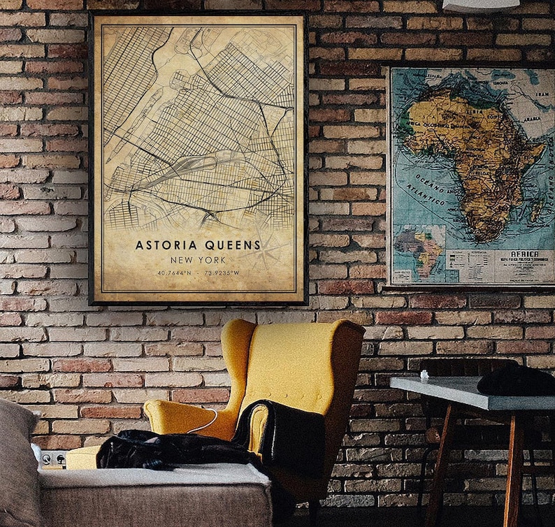 May include: A vintage style map print of Astoria, Queens, New York City. The map is framed and hanging on a brick wall. The map shows the streets and landmarks of the neighborhood. The text on the map reads "Astoria Queens, New York, 40.7644&deg;N 73.9235&deg;W".