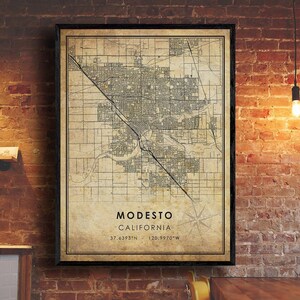May include: A vintage-style map print of Modesto, California. The map is printed on a beige background with black lines and text. The text includes the city name, state, and coordinates: Modesto, California, 37.6393°N, 120.9970°W.