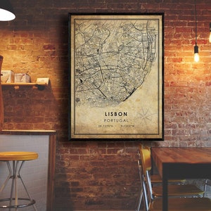 May include: A vintage-style map print of Lisbon, Portugal, with a black frame. The map shows the city's streets and landmarks. The text "LISBON PORTUGAL 38.7223&deg;N 9.1393&deg;W" is printed at the bottom of the map.