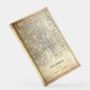 May include: Vintage style map print of Columbus, Ohio with a distressed background. The map shows the city streets and landmarks. The text "Columbus, Ohio" is printed at the bottom of the map along with the coordinates "39.9612&deg;N - 82.9988&deg;W".