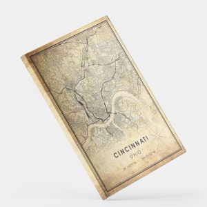 May include: Vintage style map print of Cincinnati, Ohio with a beige background and black lines. The text "Cincinnati, Ohio" is printed in black at the bottom of the map. The coordinates "39.1031&deg;N - 84.5120&deg;W" are printed in black below the city and state name.
