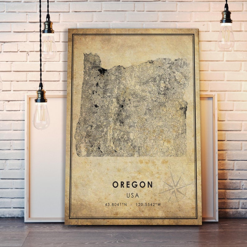 Puede incluir: Un mapa enmarcado de Oreg&oacute;n, EE. UU., con una est&eacute;tica vintage. El mapa est&aacute; detallado con carreteras y caracter&iacute;sticas geogr&aacute;ficas, sobre un fondo beige. El texto "OREGON USA" se muestra debajo del mapa, junto con las coordenadas y una rosa de los vientos.