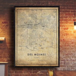 May include: A vintage-style map print of Des Moines, Iowa. The map is in black and white and shows the city's streets and landmarks. The text "Des Moines, Iowa" and the coordinates "41.5868°N - 93.6250°W" are printed at the bottom of the map.