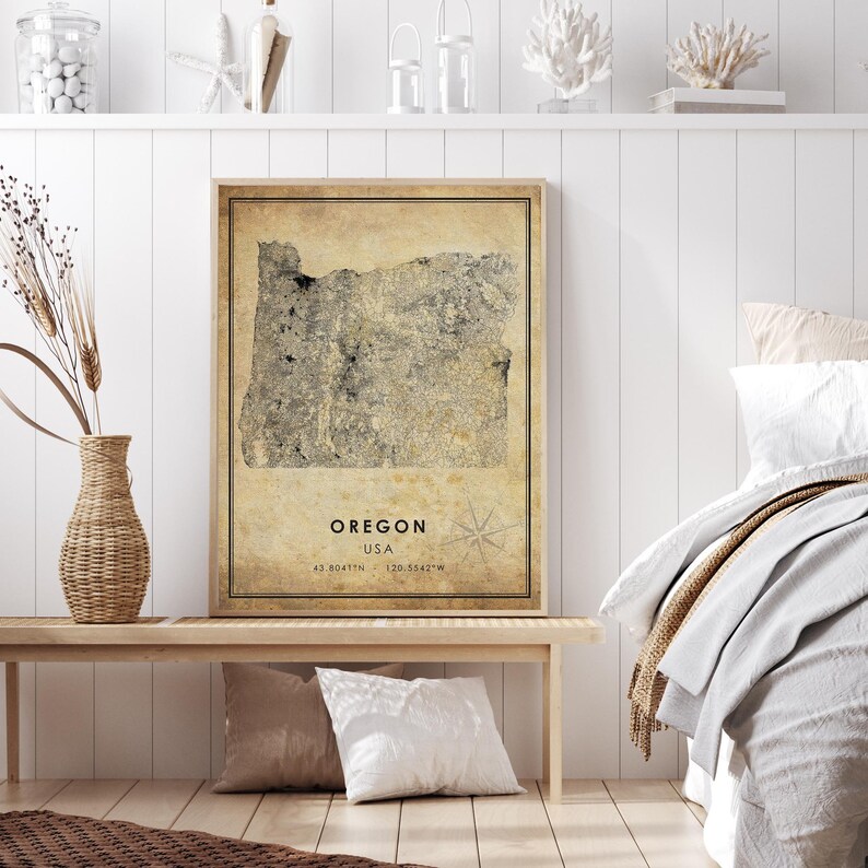 Puede incluir: Una impresi&oacute;n enmarcada del mapa de Oreg&oacute;n, EE. UU., en tonos neutros. El mapa tiene una est&eacute;tica vintage, con coordenadas y una rosa de los vientos. La impresi&oacute;n se muestra en un banco de madera con cojines decorativos y un jarr&oacute;n.