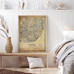 May include: A vintage-style map print of Lisbon, Portugal, with a beige background and black lines depicting streets and landmarks. The title "Lisbon, Portugal" and coordinates "38.7223&deg;N - 9.1393&deg;W" are printed below the map.