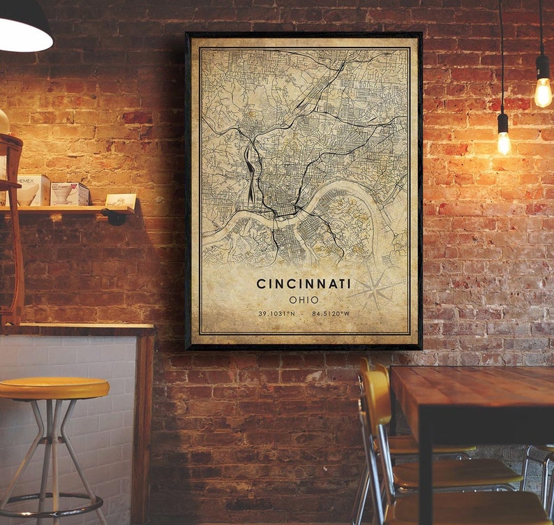 May include: A vintage-style map print of Cincinnati, Ohio, with a black frame. The map shows the city's streets and landmarks. The text "Cincinnati, Ohio" and the coordinates "39.1031&deg;N - 84.5120&deg;W" are printed below the map.