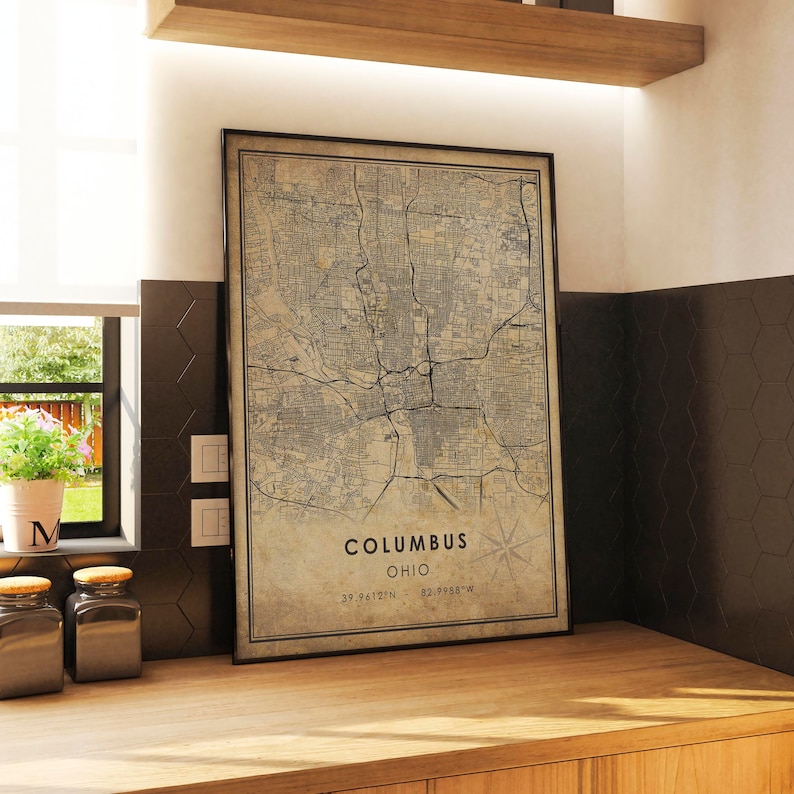 May include: A vintage-style map print of Columbus, Ohio. The map is in black and white and shows the city's streets and landmarks. The text "Columbus, Ohio" and the coordinates "39.9612&deg;N 82.9988&deg;W" are printed at the bottom of the map.