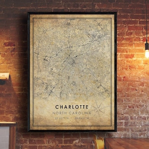 May include: A vintage-style map print of Charlotte, North Carolina, with a compass rose and the coordinates 35.2271°N, 80.8431°W. The map is printed on a textured, aged paper background.