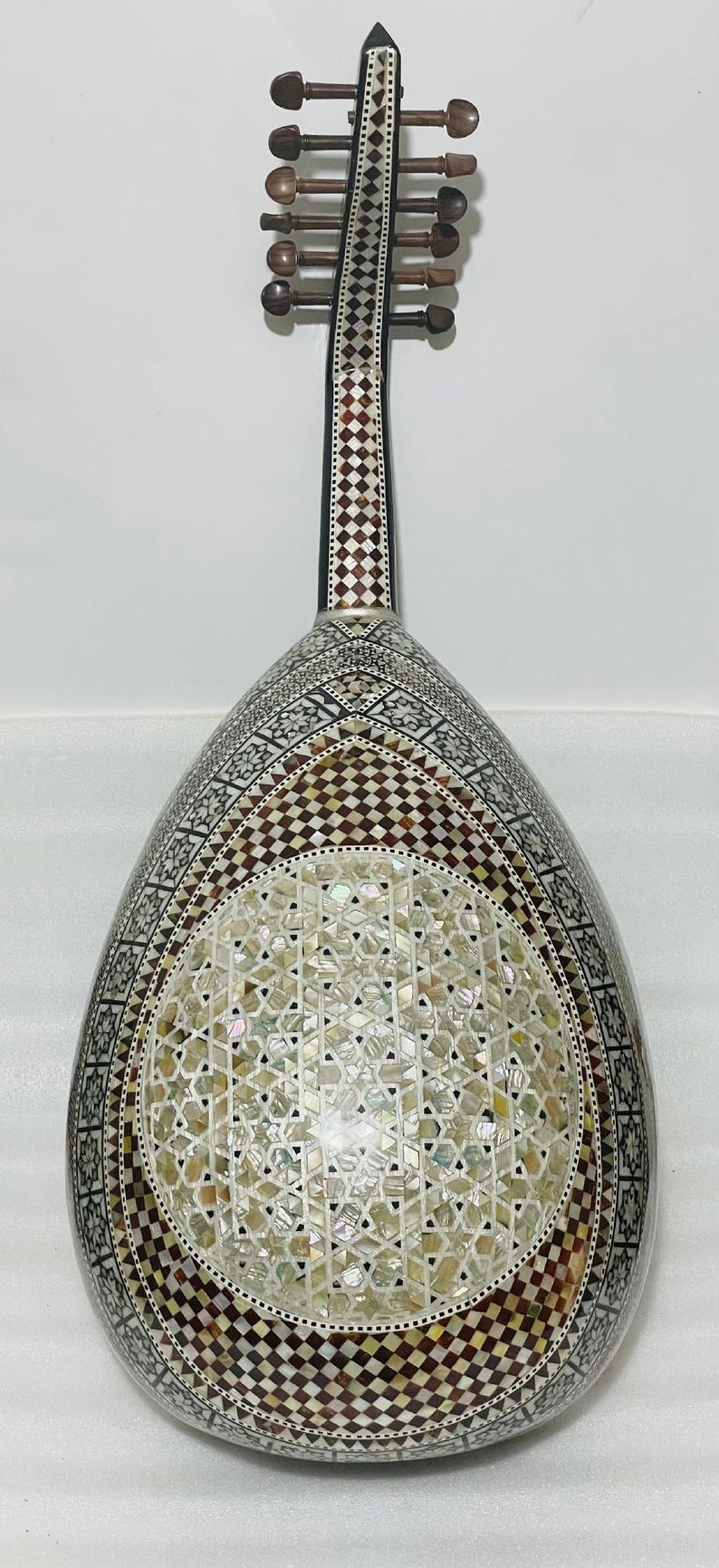 Op de afbeelding: Een ingewikkeld versierde oed, een snaarinstrument uit het Midden-Oosten. De peervormige body heeft parelmoer en geometrische patronen in bruin, wit en zwart. De hals heeft stemknoppen en decoratieve inlays.