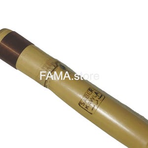 May include: Close-up of a bamboo flute with a copper-colored band near the mouthpiece. The flute has a natural, light brown color and a label with Arabic text. The text "FAMA.store" is also visible.