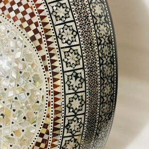 Op de afbeelding: Een handgemaakt houten bord met de tekst "Welkom" in een speels lettertype. Het bord is wit geschilderd met een verweerde afwerking en heeft een bloemenontwerp in roze en groen. Het is ongeveer 30 cm breed.