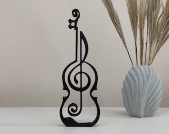 Könnte beinhalten: Schwarzer Holzausschnitt einer Geige mit einem Violinschlüssel-Design. Der Ausschnitt befindet sich auf einer weißen Oberfläche mit einer Vase mit getrockneten Blumen im Hintergrund.