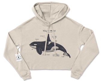 May include: A beige cropped hoodie with a black and white illustration of a killer whale with anatomical labels. The text "Killer Whale" is printed above the illustration.