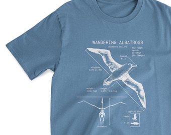 Op de afbeelding: Een blauw T-shirt met een witte afbeelding van een zwervende albatros, die zijn vleugelspanwijdte, hoogte, gewicht en typische dieet laat zien. De afbeelding bevat ook een skeletdiagram van de vogel. De tekst op het T-shirt luidt "Zwervende albatros, Diomedea exulans, Gekromde snavel, Topsnelheid in de vlucht: 96-128 km/u, Vleugelspanwijdte: 11 voet (3,4 m), Gewicht: 16 pond (7 kg), Hoogte: 3-4 voet (0,9-1,2 m), Typisch dieet: Inktvis, Vis, Skelet."